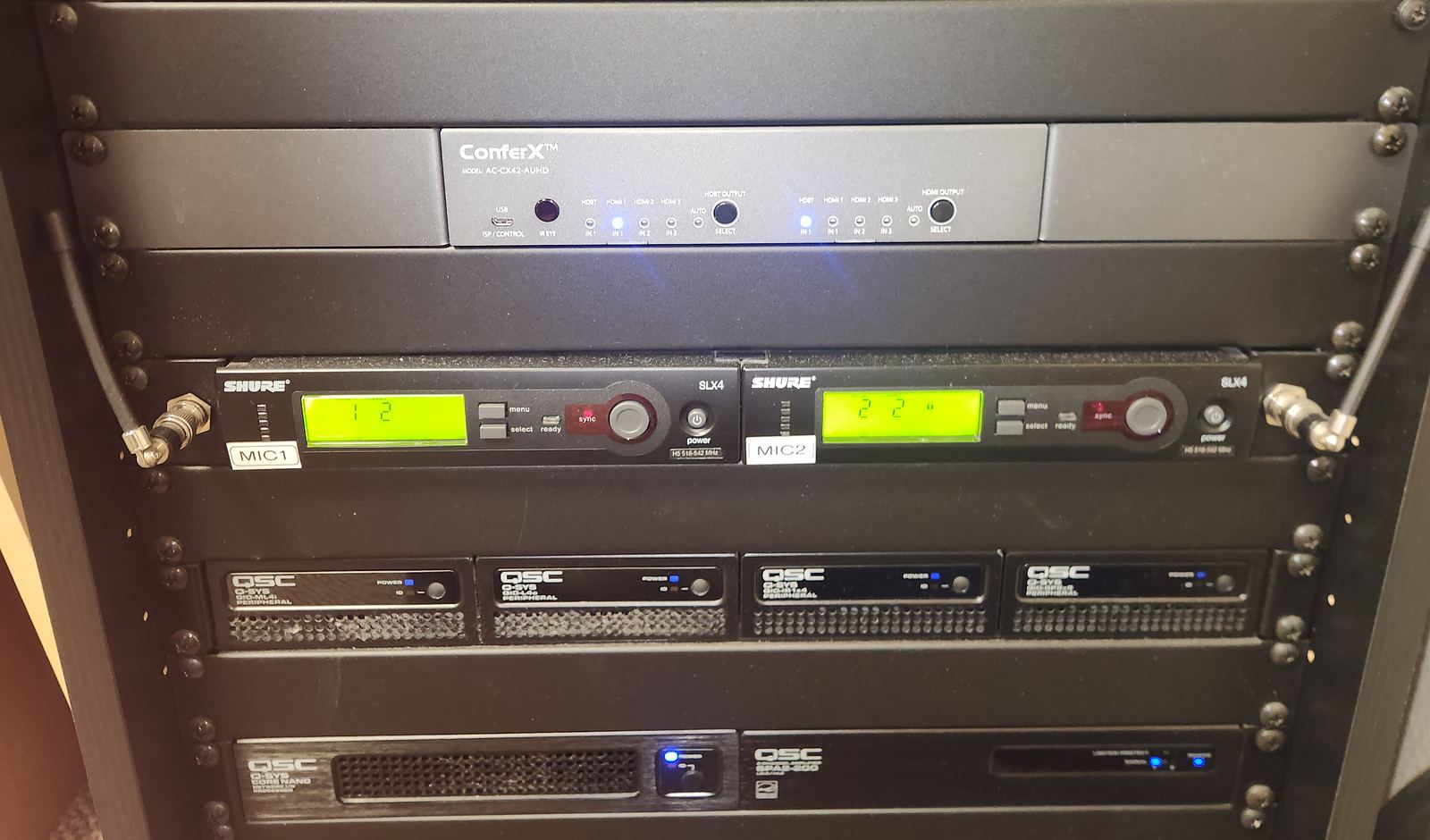 An equipment rack with a video switcher, two wireless microphone receivers and several amplifiers